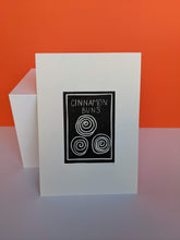 Load image into Gallery viewer, Black and white cinnamon buns print on an orange background
