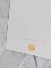 Load image into Gallery viewer, A white card with a yellow logo on the back