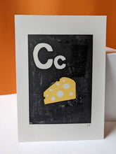 Load image into Gallery viewer, A black and yellow print of a block of cheese and the letter C against on orange background
