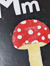 Load image into Gallery viewer, A black print with a red mushroom and the letter M carved out of it
