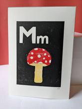 Load image into Gallery viewer, A black print with a red mushroom and the letter M carved out of it
