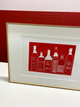 Load image into Gallery viewer, A red print of wine bottles framed in a thin oak wood frame
