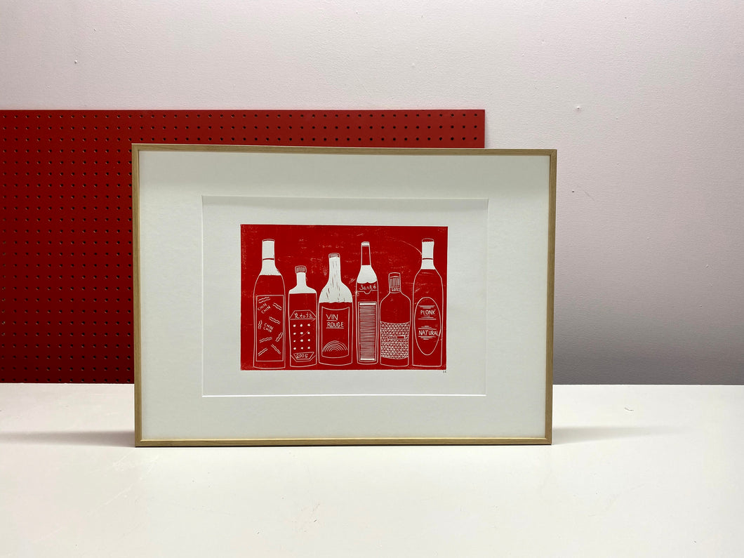 A red print of wine bottles framed in a thin oak wood frame