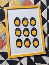 Load image into Gallery viewer, A white print with 9 black and yellow boiled eggs printed on in a yellow frame

