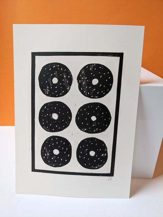 A black and white print of six sesame bagels against an orange background