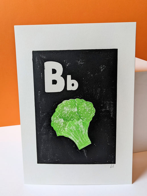 A black and white print with a green broccoli printed on, with an orange background