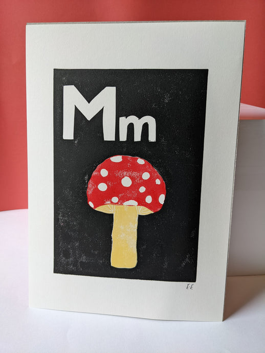 A black print with a red mushroom and the letter M carved out of it